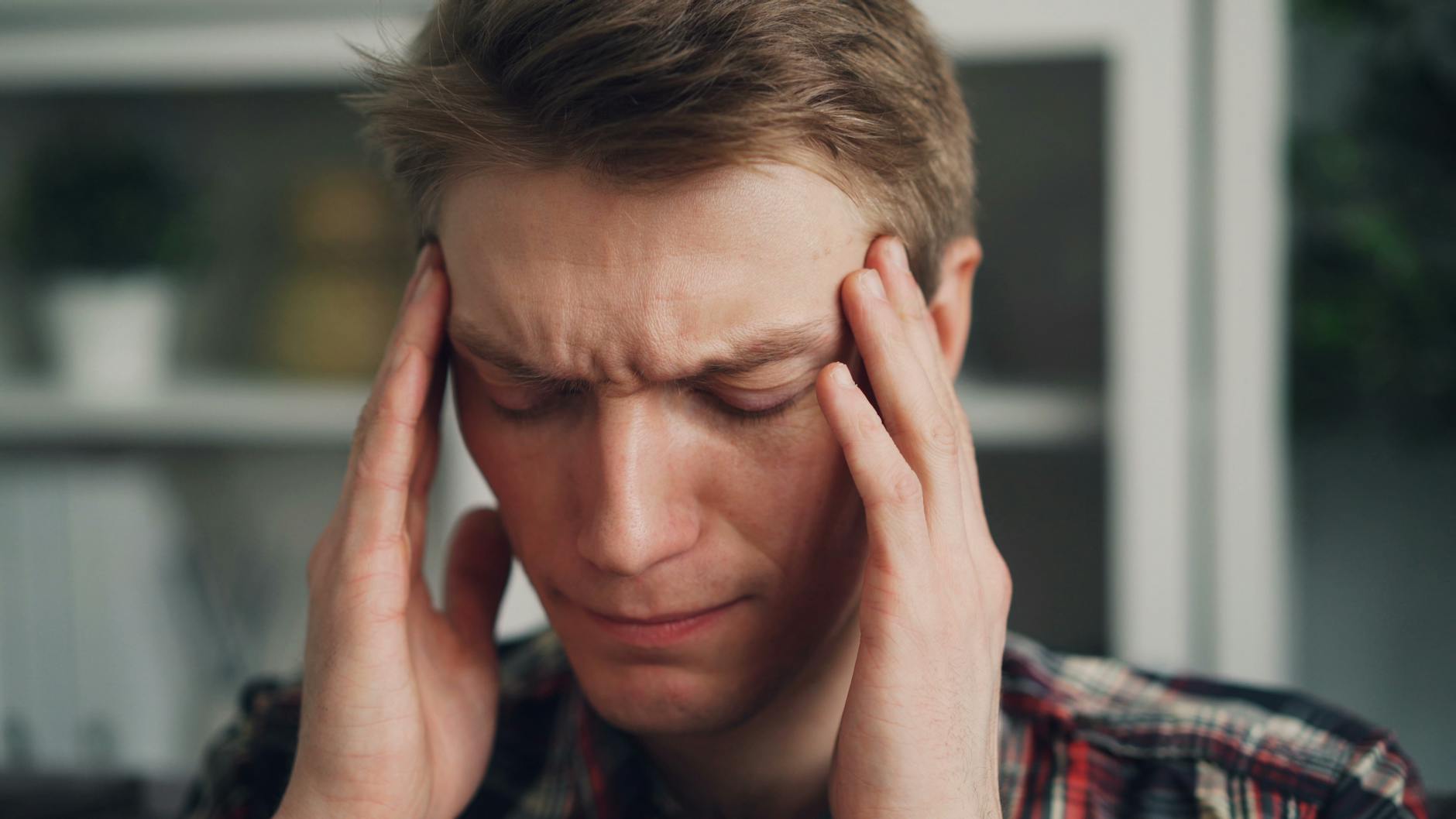 man rubbing his temples with a worried look on his face
