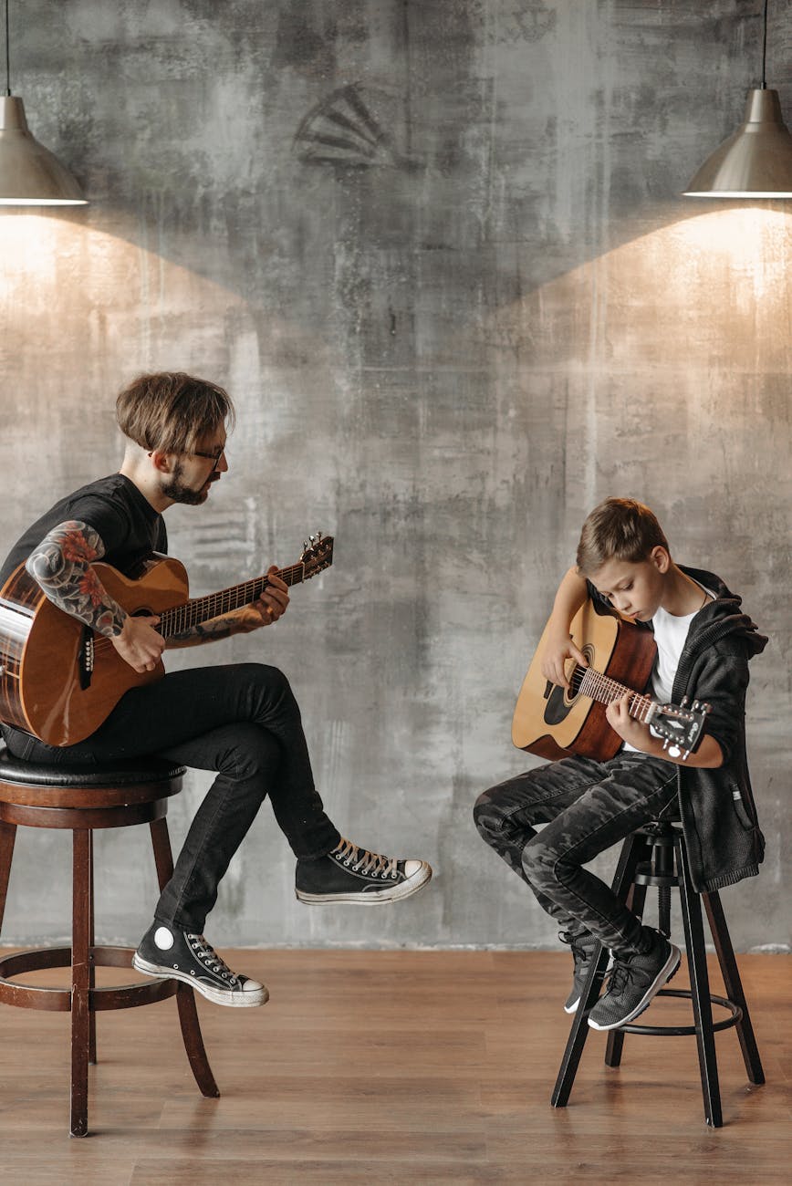 a tattooed man and a young boy playing guitar together