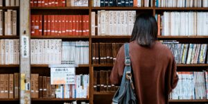 woman wearing brown shirt carrying black leather bag on front of library books