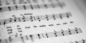 Close-up of black and white sheet music featuring musical notes and lyrics in focus.